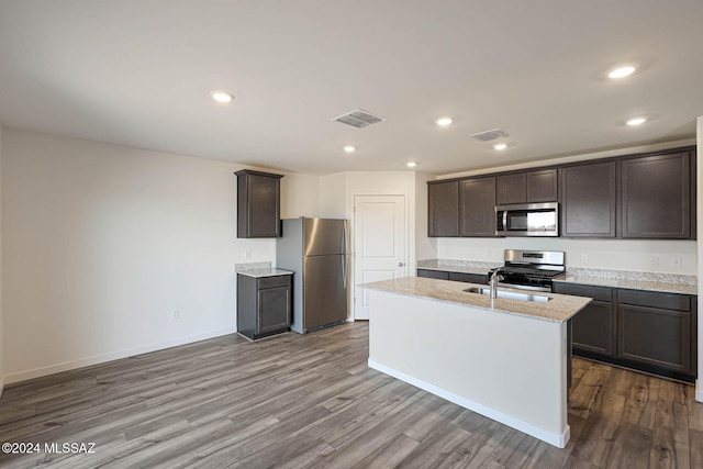 kitchen with appliances with stainless steel finishes, light hardwood / wood-style floors, sink, and an island with sink