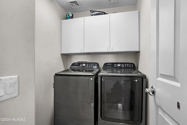 clothes washing area featuring cabinets and separate washer and dryer