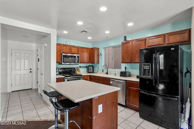 kitchen featuring stainless steel appliances, sink, a breakfast bar, light tile patterned floors, and a kitchen island