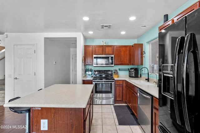 kitchen featuring light hardwood / wood-style floors, stainless steel appliances, a center island, sink, and a breakfast bar area