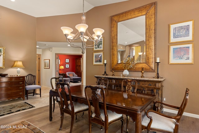 dining room with lofted ceiling, light hardwood / wood-style flooring, and an inviting chandelier