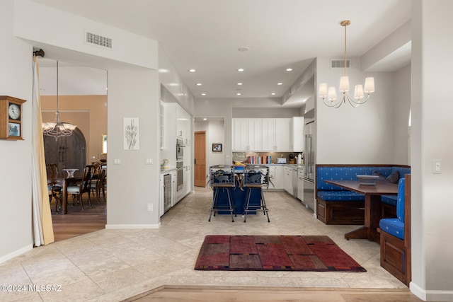 kitchen featuring a breakfast bar, a center island, a notable chandelier, decorative light fixtures, and white cabinetry