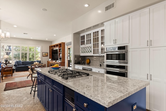 kitchen featuring a center island, blue cabinets, white cabinetry, stainless steel appliances, and decorative backsplash