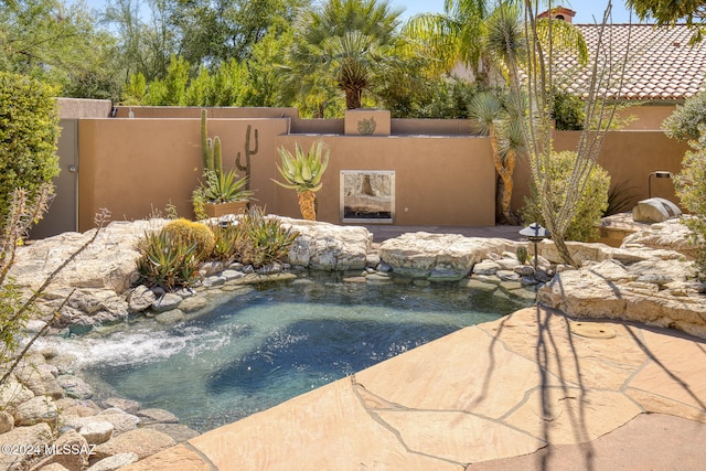 view of swimming pool with a small pond and a patio