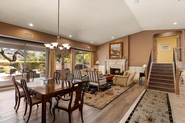 dining room featuring light hardwood / wood-style flooring, lofted ceiling, and a chandelier