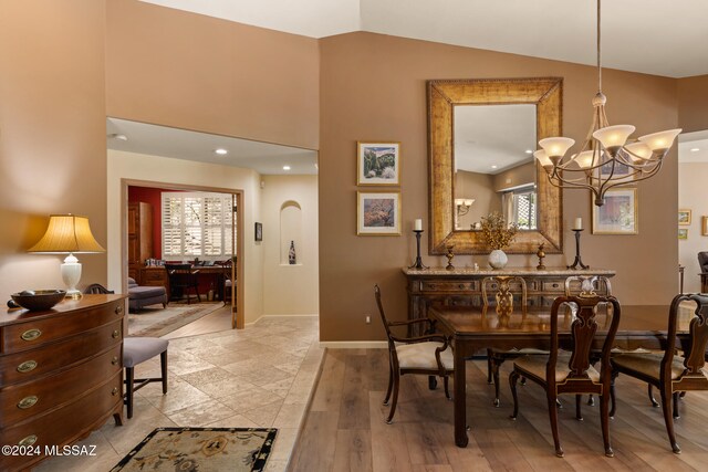 dining area with vaulted ceiling, light hardwood / wood-style flooring, and a chandelier