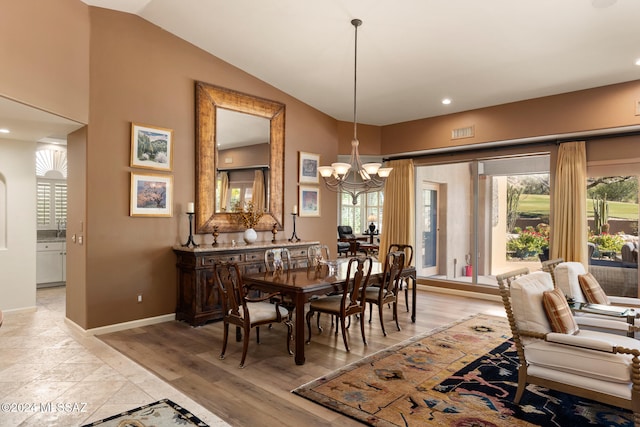 dining room with vaulted ceiling, light hardwood / wood-style flooring, and a chandelier