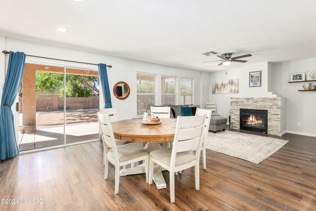 dining room featuring hardwood / wood-style floors, ceiling fan, a healthy amount of sunlight, and a fireplace