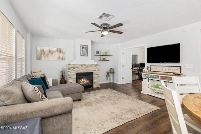 living room with a textured ceiling, dark hardwood / wood-style floors, ceiling fan, and a fireplace