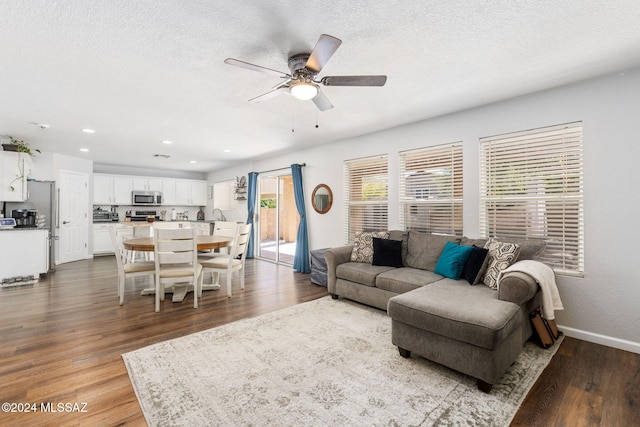 living room with hardwood / wood-style floors, ceiling fan, and a textured ceiling