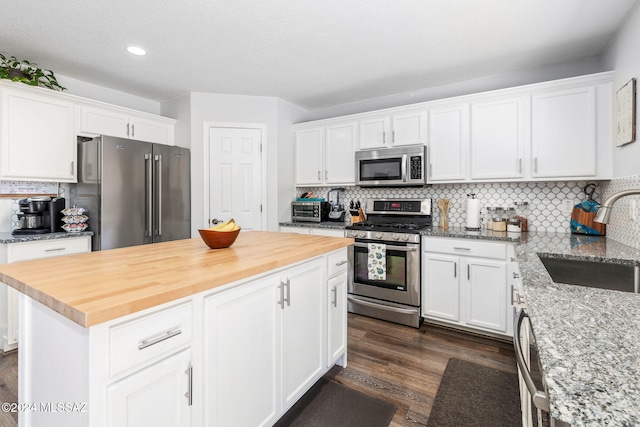 kitchen featuring tasteful backsplash, stainless steel appliances, sink, white cabinets, and a center island