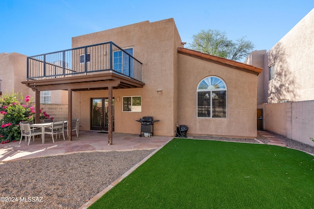 back of property with a yard, a patio area, and a balcony