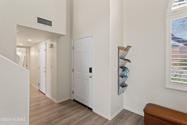 entryway with a towering ceiling and light hardwood / wood-style flooring