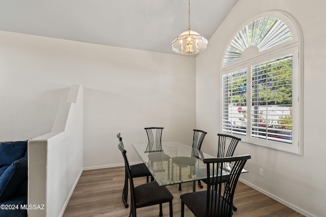 dining space featuring a chandelier, hardwood / wood-style flooring, vaulted ceiling, and a wealth of natural light