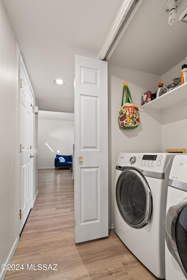 washroom with washing machine and dryer and light hardwood / wood-style floors