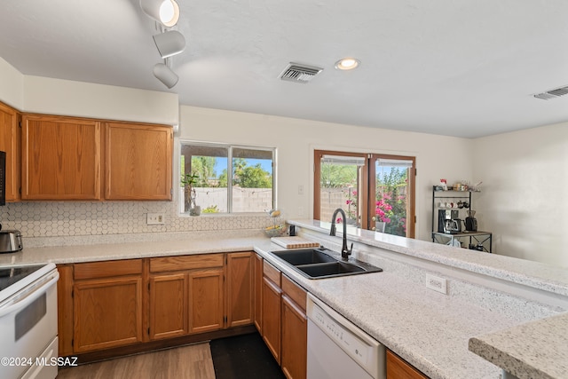 kitchen featuring sink, light stone counters, backsplash, white appliances, and light wood-type flooring