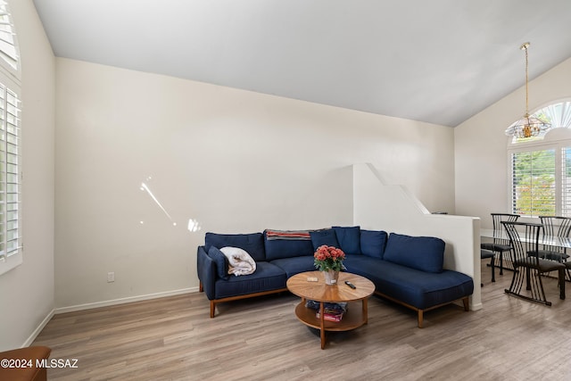 living room featuring wood-type flooring, an inviting chandelier, and lofted ceiling