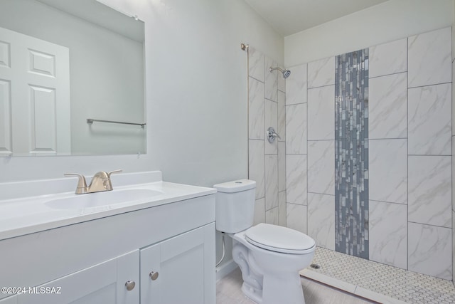 bathroom featuring vanity, tiled shower, and toilet