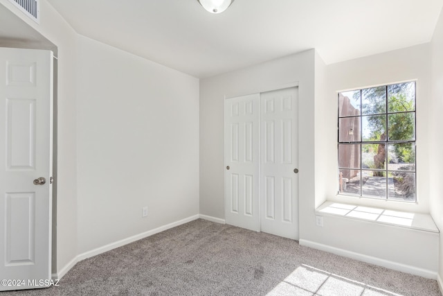 unfurnished bedroom featuring light colored carpet and a closet