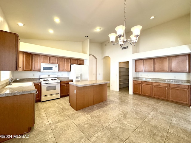 kitchen featuring white appliances, sink, pendant lighting, an inviting chandelier, and a kitchen island