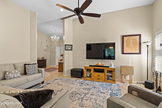 tiled living room with a towering ceiling and ceiling fan with notable chandelier