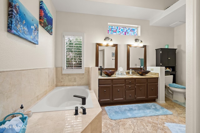 bathroom featuring vanity, toilet, and a relaxing tiled tub