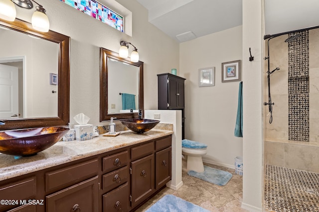 bathroom featuring vanity, toilet, and a tile shower