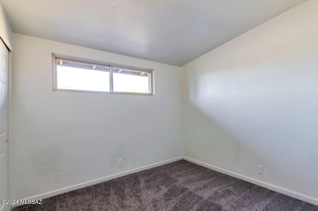 empty room with dark colored carpet and baseboards