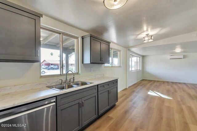kitchen with gray cabinets, stainless steel dishwasher, light wood-style floors, light countertops, and a sink