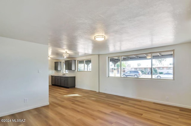 unfurnished living room featuring light wood-type flooring, baseboards, and a sink