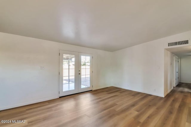 empty room with baseboards, visible vents, wood finished floors, and french doors