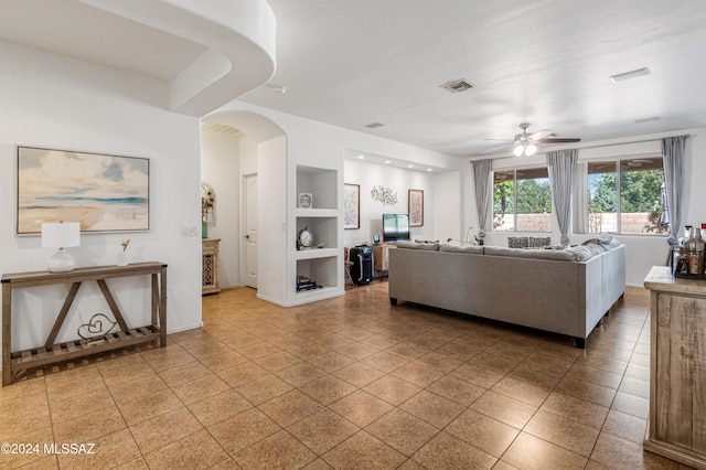 tiled living room with ceiling fan and built in features