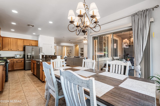 dining space with light tile patterned floors, ceiling fan with notable chandelier, and sink