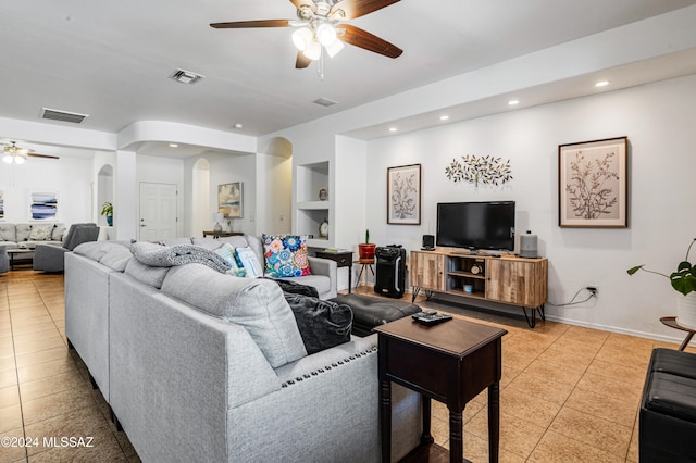 living room featuring ceiling fan, built in features, and light tile patterned floors