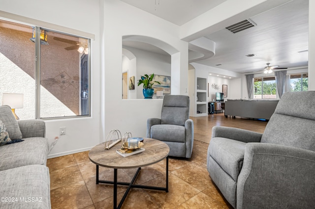 tiled living room with ceiling fan and built in features