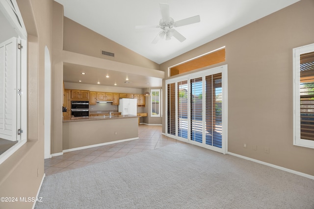 unfurnished living room with vaulted ceiling, a wealth of natural light, light tile patterned floors, and ceiling fan