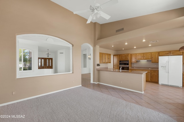 kitchen with ceiling fan, white fridge with ice dispenser, kitchen peninsula, and light colored carpet