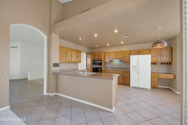 kitchen featuring stainless steel double oven, white fridge with ice dispenser, sink, light tile patterned floors, and light stone counters