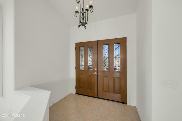 entryway featuring a notable chandelier, vaulted ceiling, and light tile patterned floors