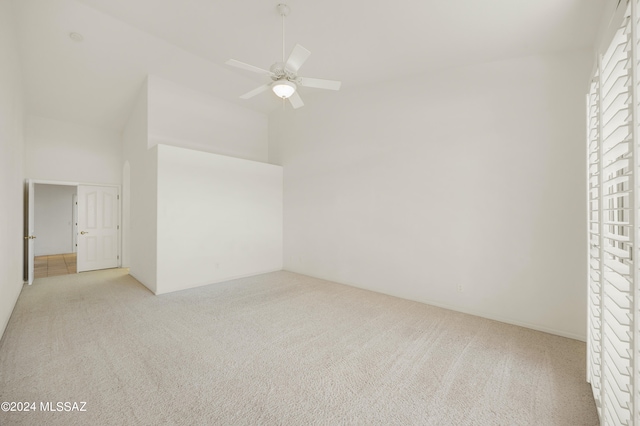 spare room featuring ceiling fan, a high ceiling, and light colored carpet