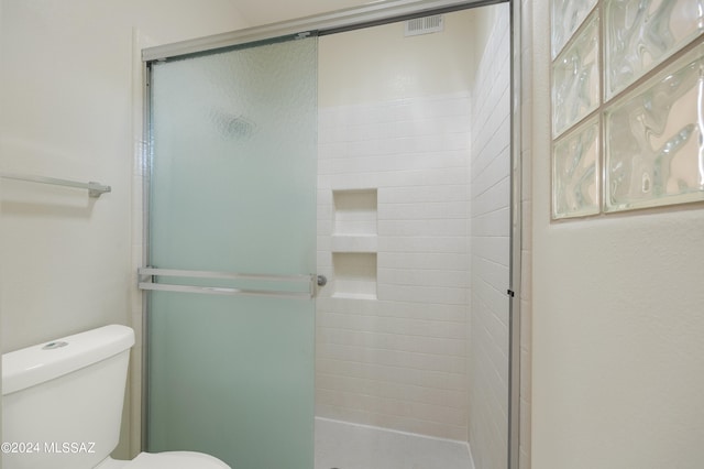 bathroom with a shower with door and toilet