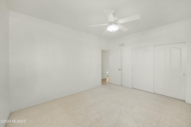 unfurnished bedroom featuring light colored carpet, a closet, and ceiling fan