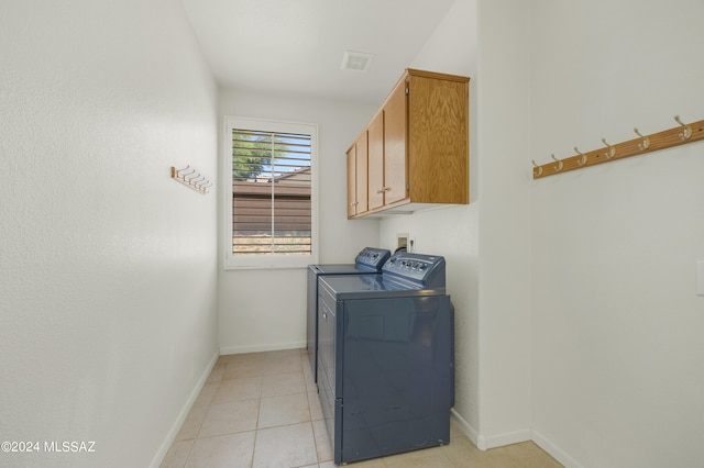 laundry area featuring light tile patterned flooring, washing machine and dryer, and cabinets