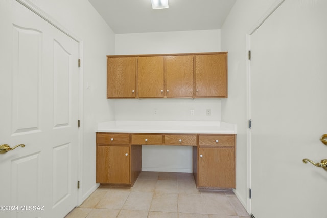 unfurnished office featuring built in desk and light tile patterned floors