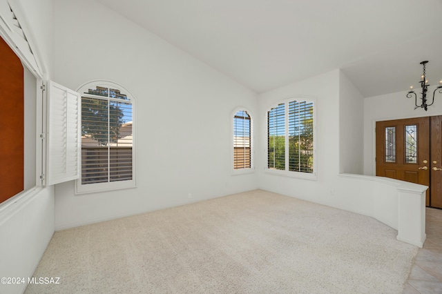 interior space with light carpet, vaulted ceiling, and a chandelier