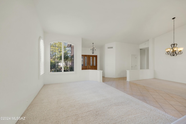 tiled spare room with a notable chandelier