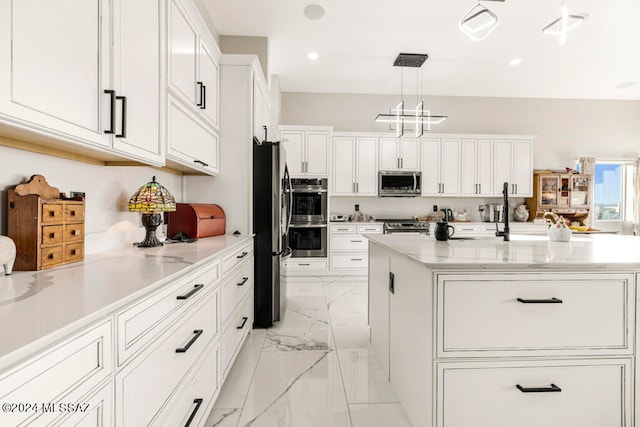 kitchen featuring appliances with stainless steel finishes, white cabinetry, pendant lighting, and an island with sink