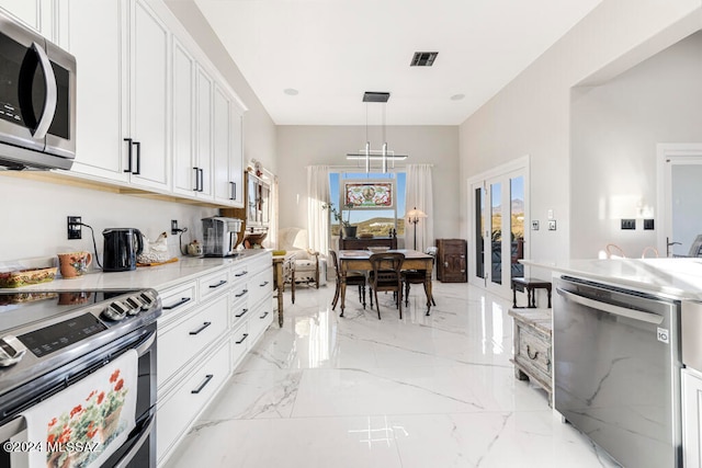 kitchen with french doors, stainless steel appliances, light stone countertops, pendant lighting, and white cabinets