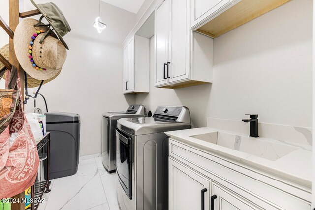 clothes washing area featuring cabinets, sink, and washer and clothes dryer