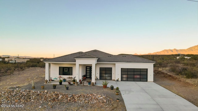 prairie-style home featuring a porch, a mountain view, and a garage